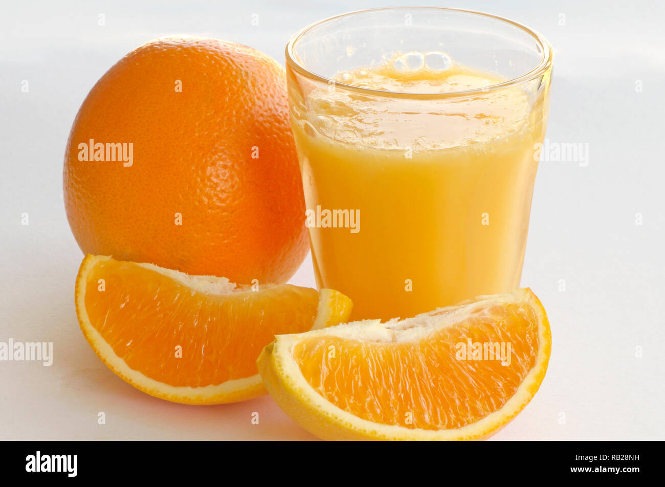Un verre de jus d'orange d'un ensemble orange Navel (Citrus sinensis x) et deux des quartiers d'orange sur un fond blanc. Banque D'Images