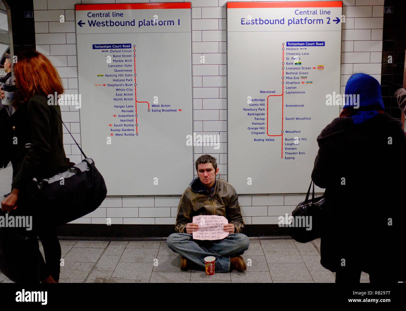 un jeune homme sans abri se trouve près des quais de la ligne centrale sur le métro de londres pour demander de l'aide pendant les mois d'hiver Banque D'Images