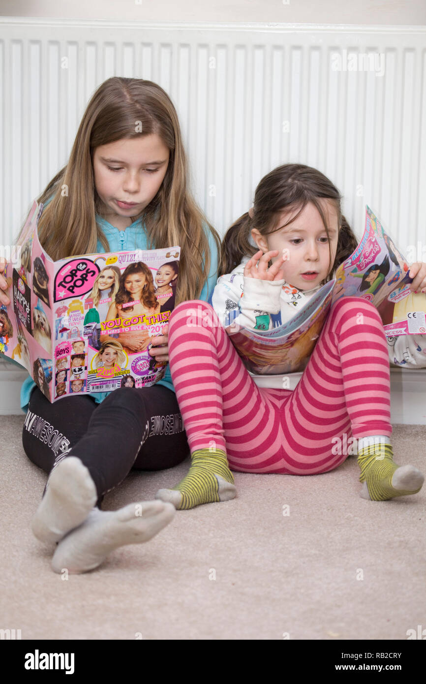 Les enfants la lecture de revues à la maison Banque D'Images