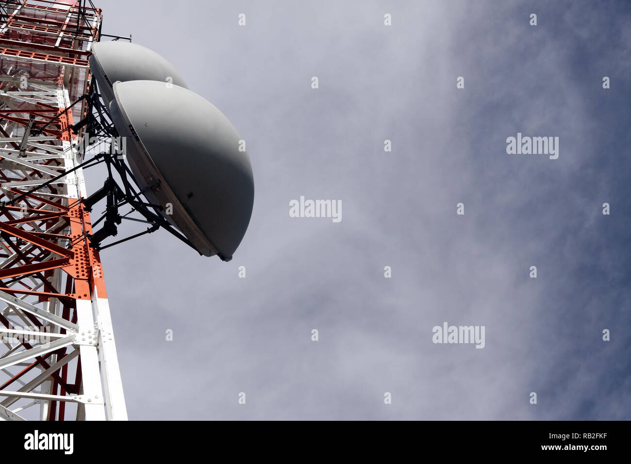 Partie d'une tour de communications avec les antennes contre ciel nuageux Banque D'Images