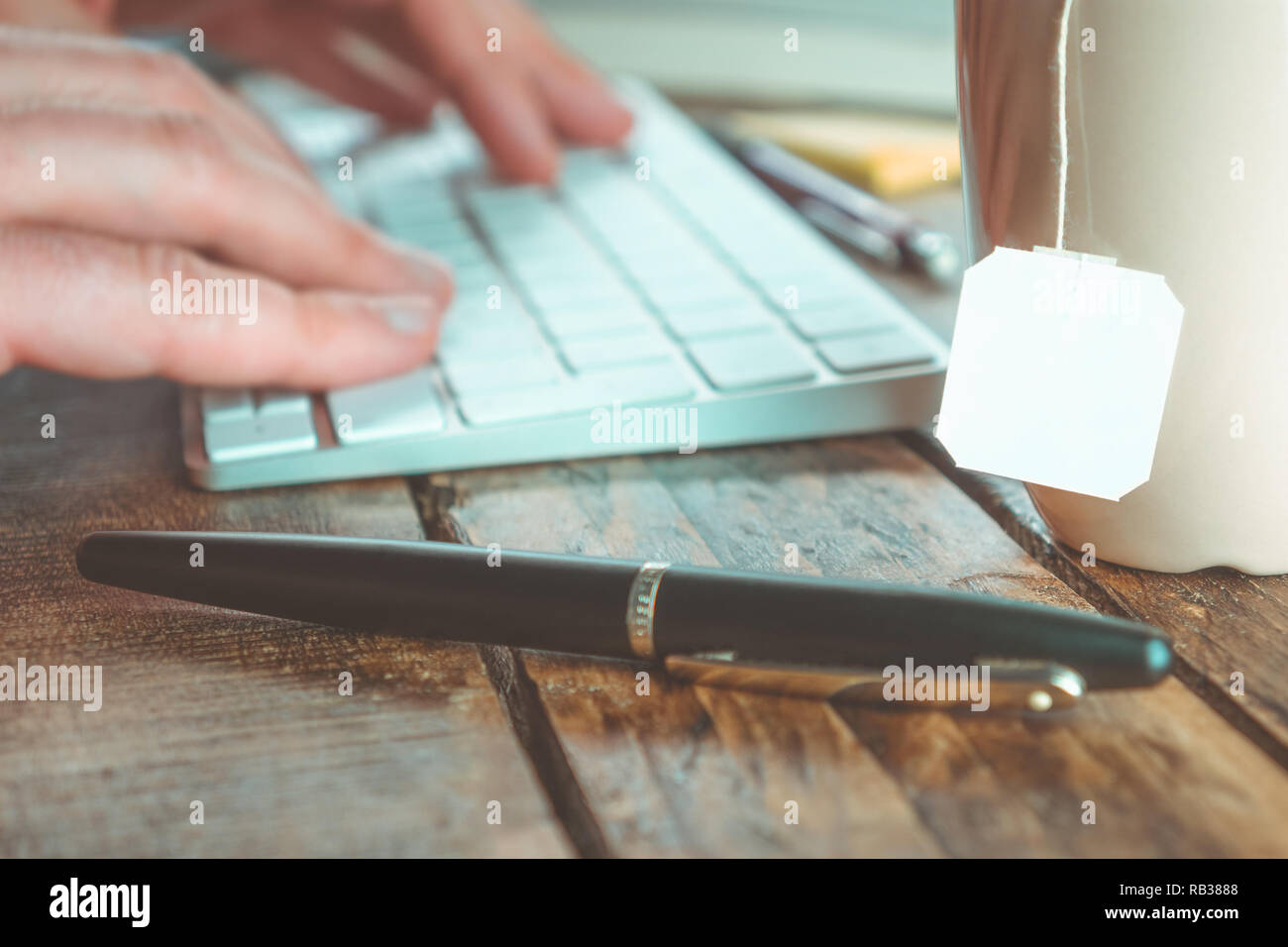 Close-up de l'espace de travail avec les mains sur un clavier et copie blanche de l'espace sur la tasse de thé. Le travail de bureau concept. Banque D'Images