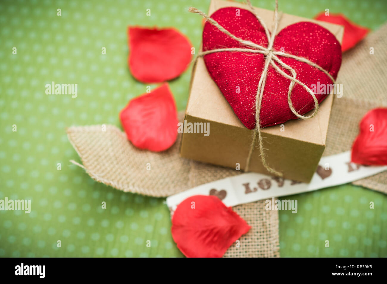 Valentine day. Un cœur rouge attaché avec un vieux thread pour une boîte-cadeau se trouve sur un fond bleu à pois vert. Le jour de la Saint-Valentin. Pendentif Coeur. L'espace pour le texte. Banque D'Images