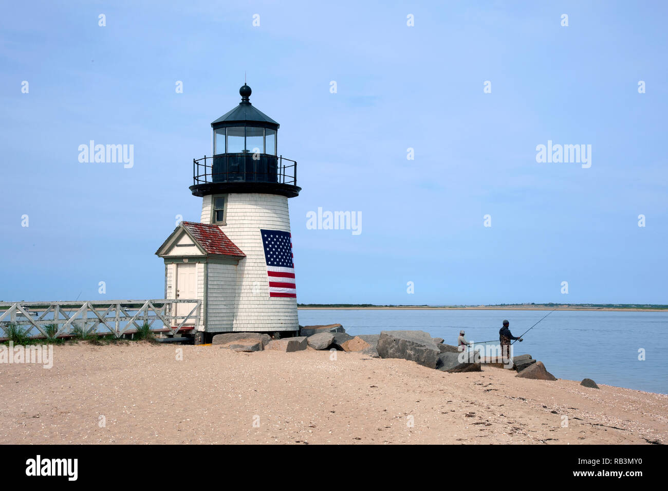 La pêche au large de la plage de sable par Brent Point Lighthouse sur l'île de Nantucket dans Masssachusetts. La balise est enveloppé dans un drapeau américain. Banque D'Images