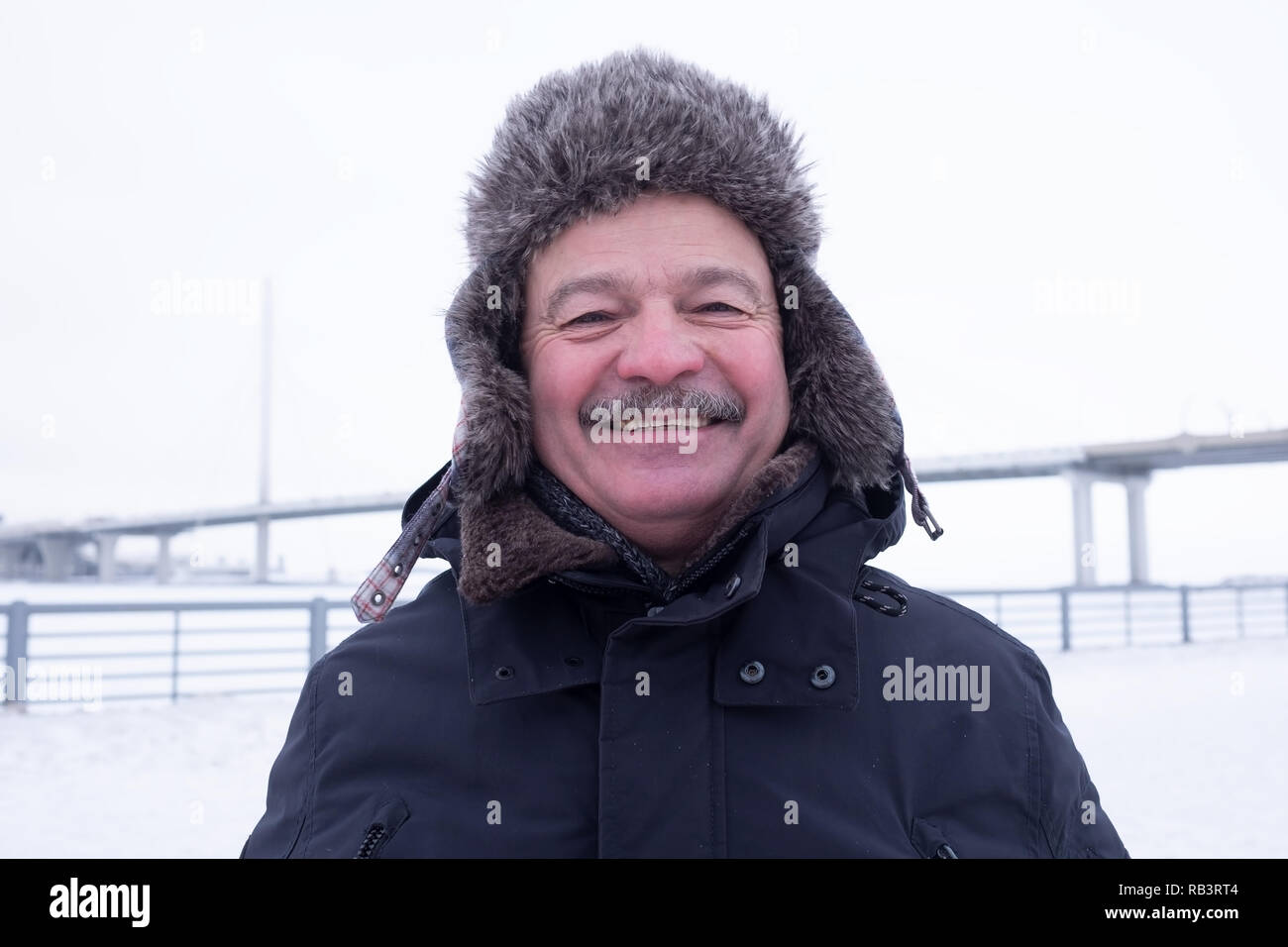 Close up portrait of smiling charmant papi avec moustache. Grand-père à l'extérieur enneigé portant chapeau chaud Banque D'Images