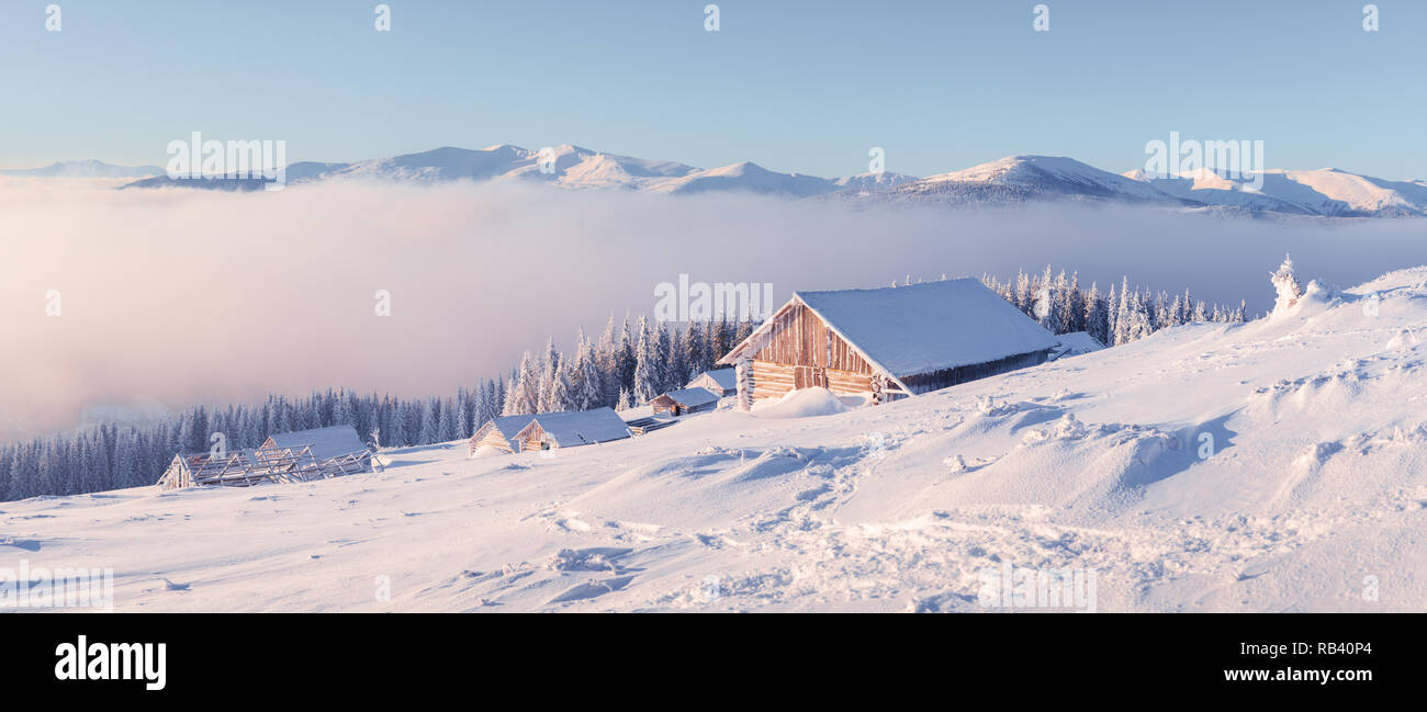 Paysage d'hiver fantastique avec maison en bois dans les montagnes enneigées. Concept de vacances de Noël Banque D'Images