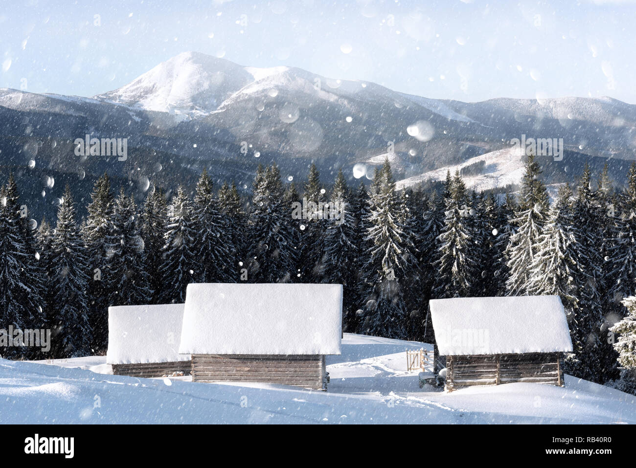 Paysage d'hiver fantastique avec maison en bois dans les montagnes enneigées. Carte postale de vacances de Noël collage. Lumière effet bokeh DOF post-traitement Banque D'Images