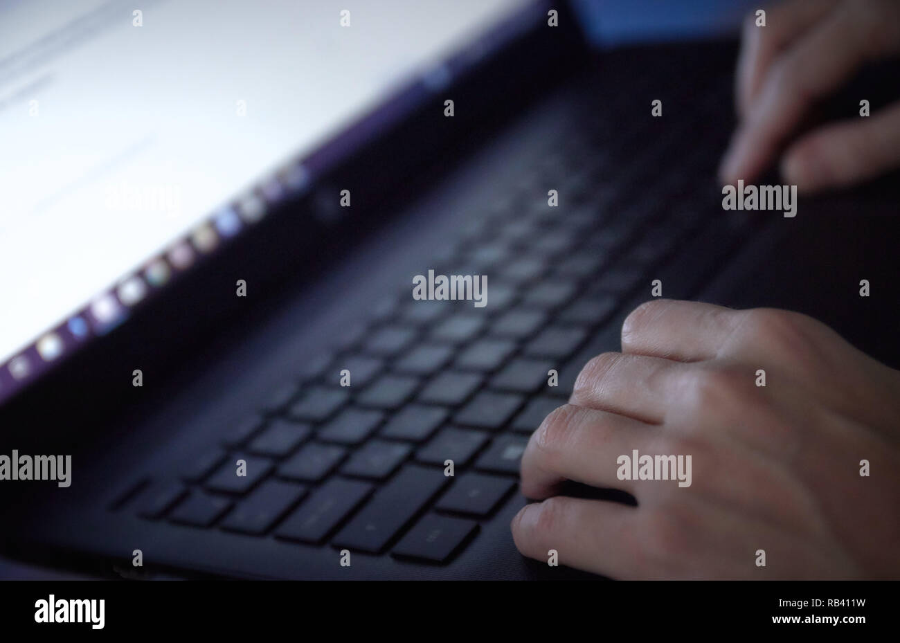 Woman working on laptop in office part sur le clavier près. dans un environnement sombre. Banque D'Images