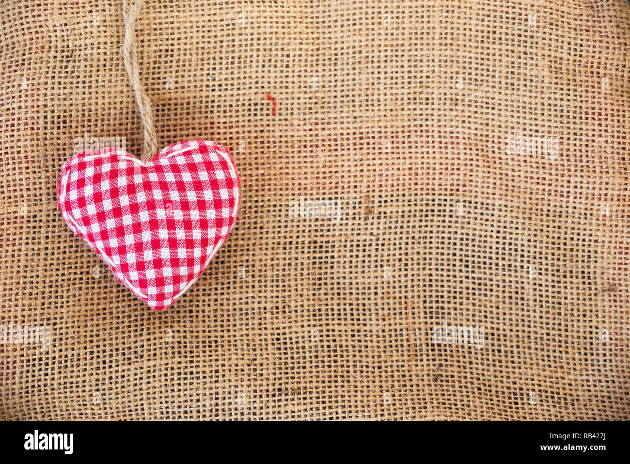Coeur en tissu rouge sur fond de toile rustique Banque D'Images