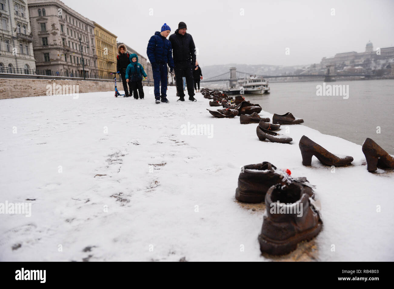 Une famille semble marcher par le memorial chaussures sur la rive du Danube, un mémorial en l'honneur des Juifs qui ont été tués par des miliciens fascistes flèche croisée à Budapest pendant la Seconde Guerre mondiale. Banque D'Images