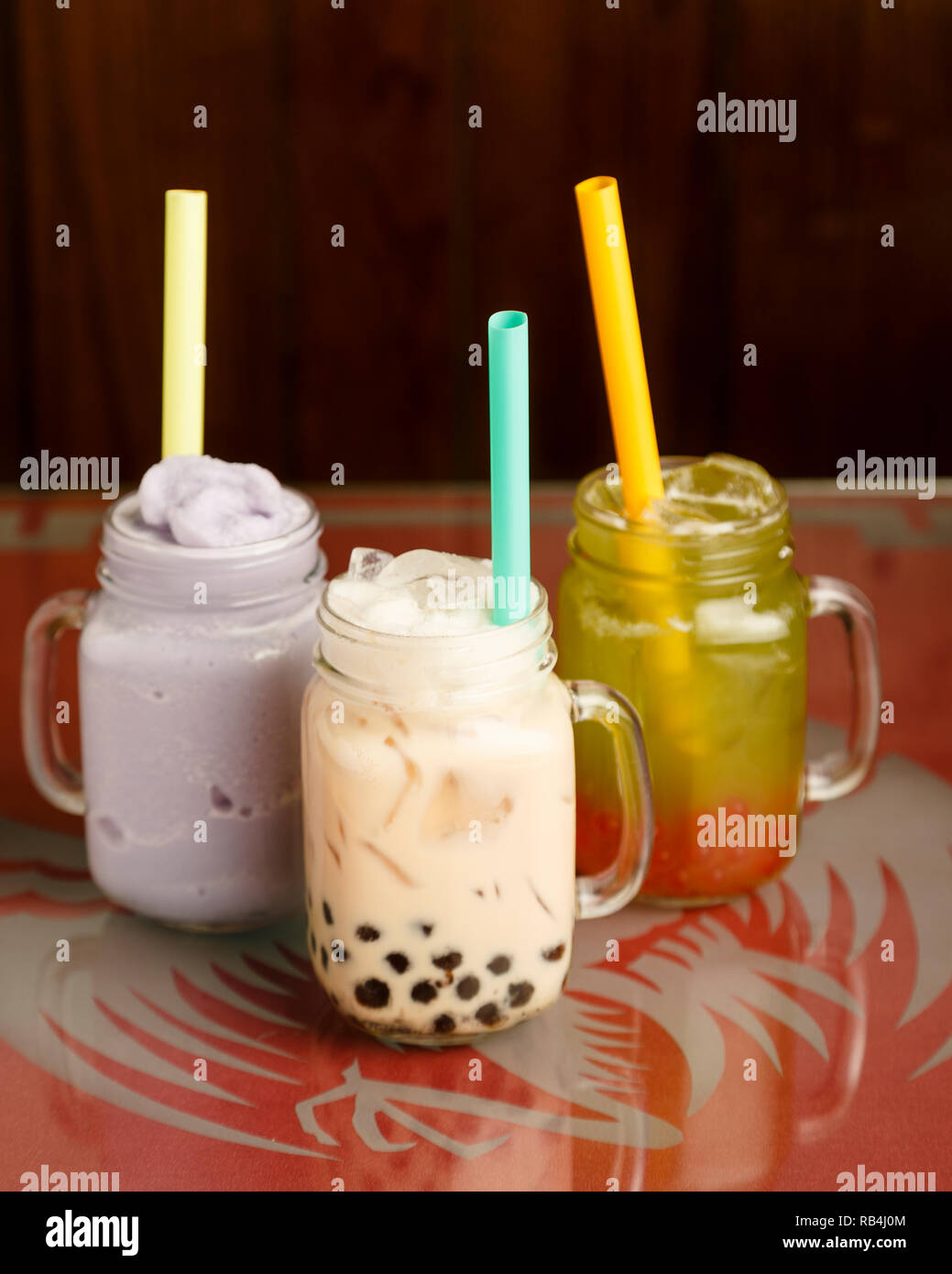De gauche à droite : taro, smoothie lait noir plateau avec du miel de miellat boba, le thé vert à la fraise popping boba sur une table dans un restaurant chinois Banque D'Images