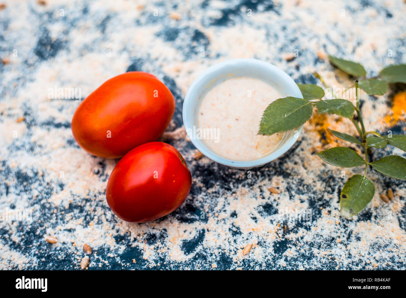 Close up of meilleure huile Dépose et ayurvédiques organique,pack face de la tomate et de l'avoine avec de l'eau sur la surface en bois avec certaines feuilles et pétales de rose. Banque D'Images