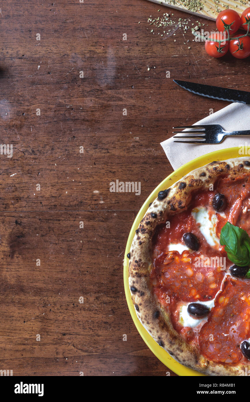 Vue de dessus le fond italien pizza napolitaine avec pepperoni, salami, fromage, olives noires et basilic. composition du châssis avec des ingrédients d'espace libre pour t Banque D'Images