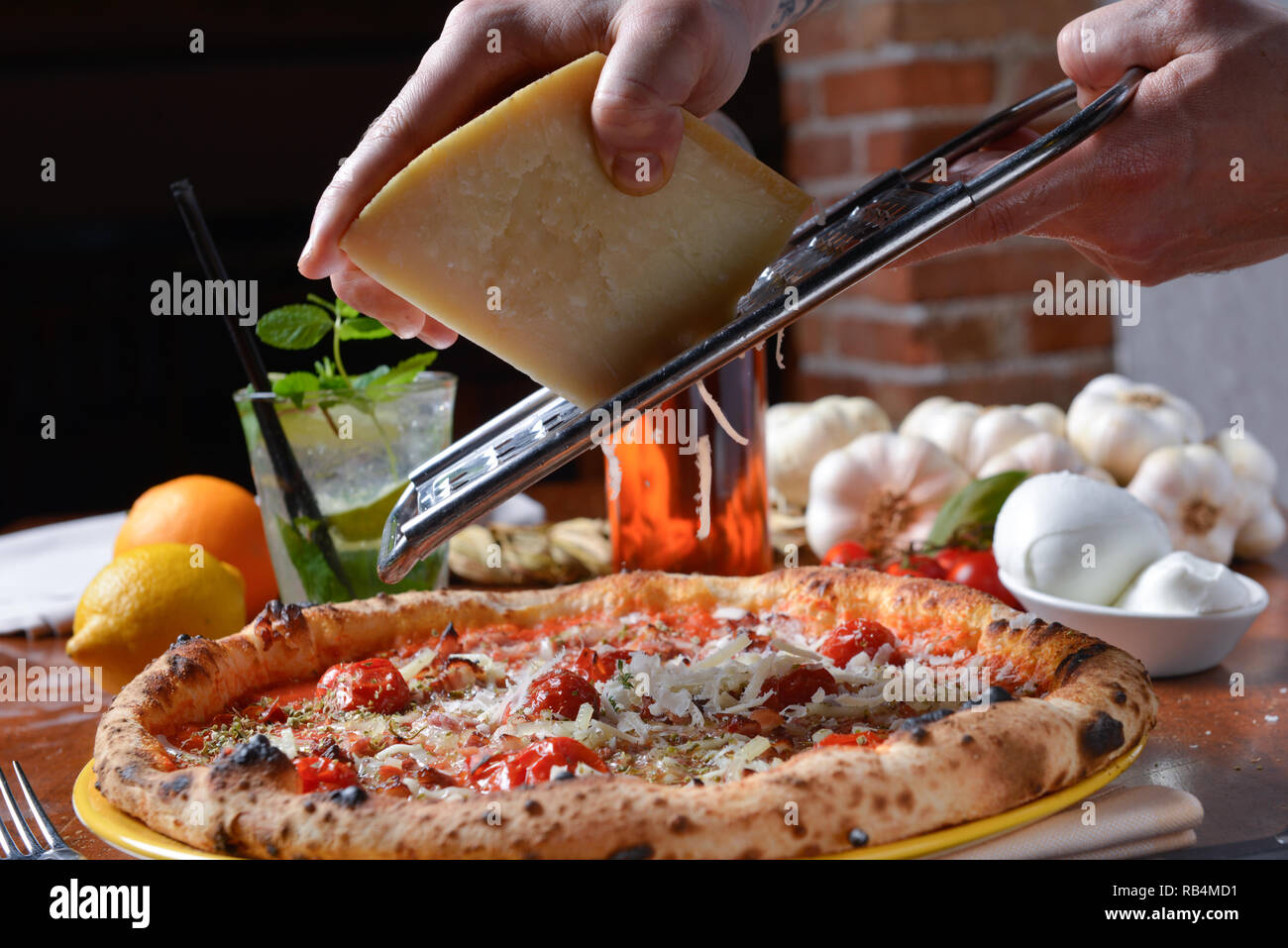 Pizza vinaigrette après cuisson râper le parmesan avec les mains Banque D'Images