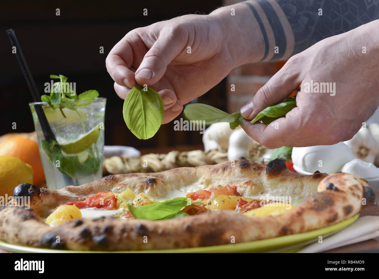 Pizza vinaigrette après cuisson mettre du basilic frais leafs avec les mains Banque D'Images