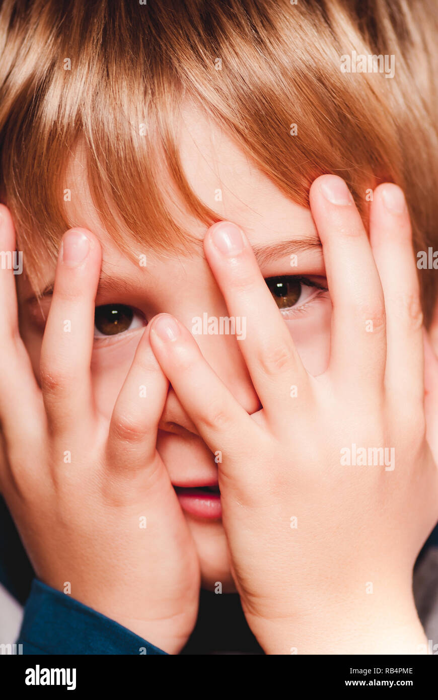 Petit enfant avec les mains sur le visage - connexions sensorielles Banque D'Images