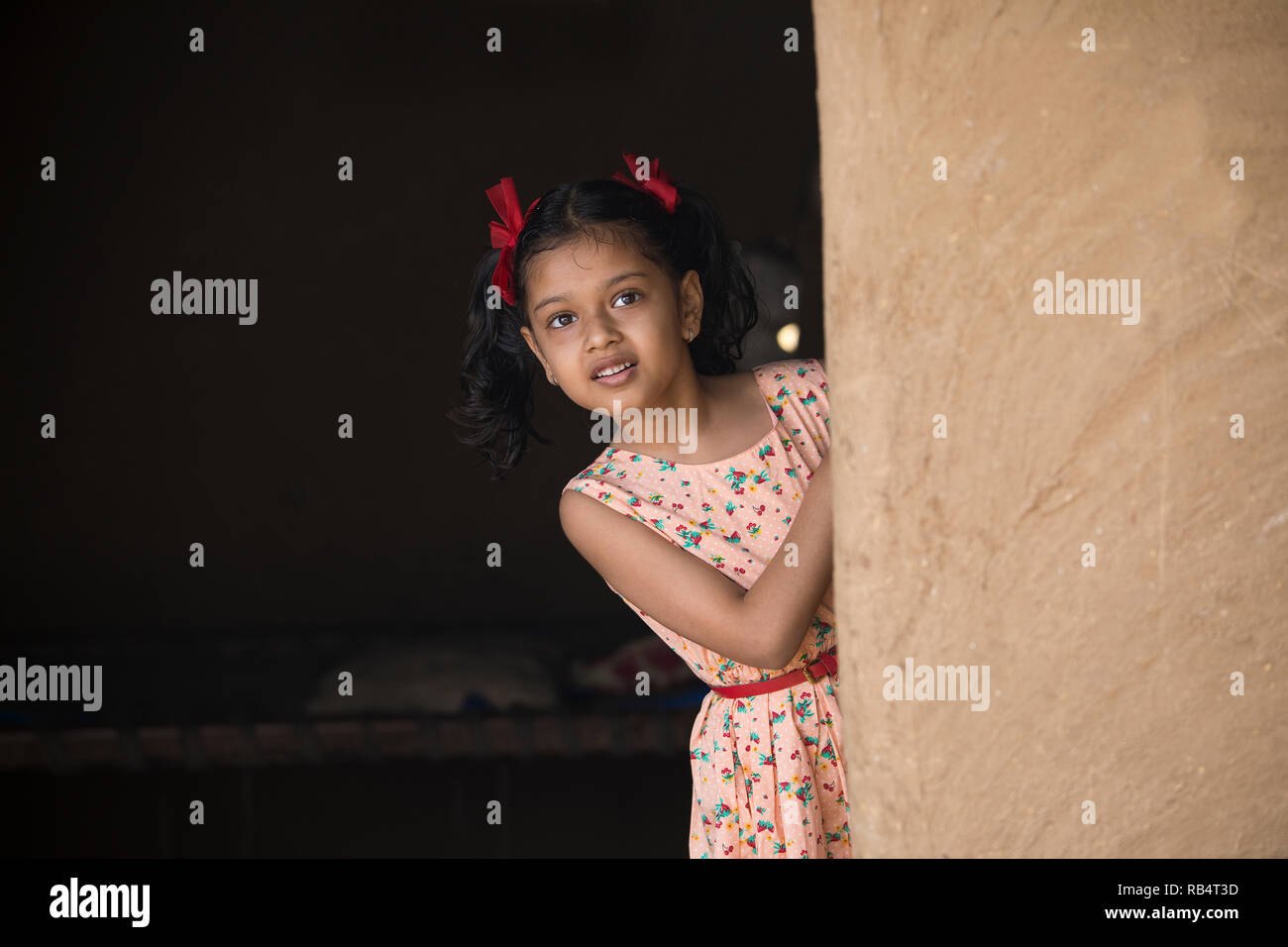 Little Indian girl peeking out de sa maison dans village Banque D'Images
