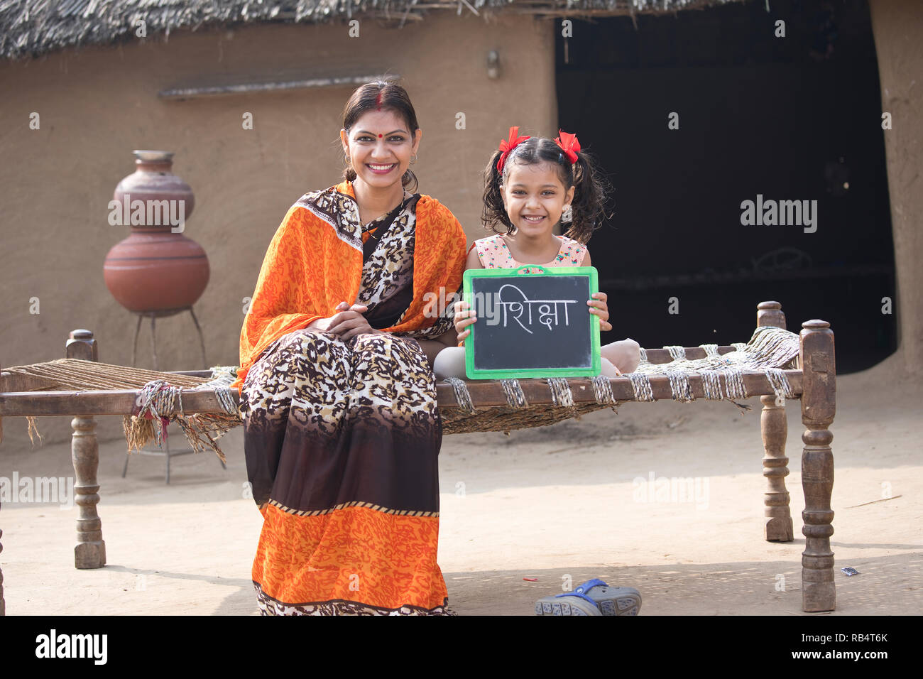 Heureuse mère indienne avec sa fille tenant assis sur ardoise lit traditionnel dans le village Banque D'Images