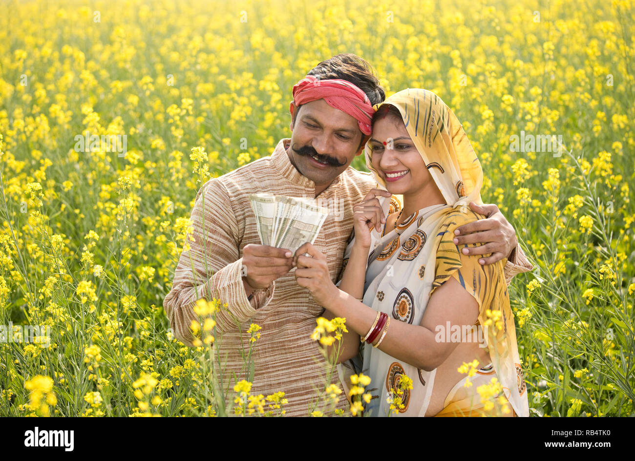 Heureux agriculteur indien avec wife holding Indian Rupee notes dans le champ de l'agriculture Banque D'Images