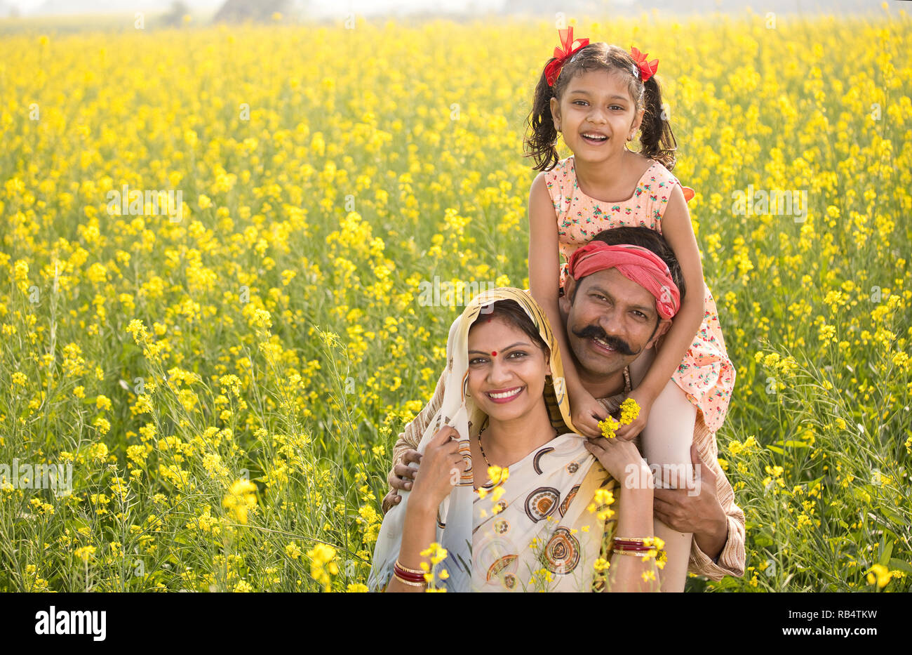 Portrait de famille de l'Inde rurale heureux dans le colza champ agricole Banque D'Images