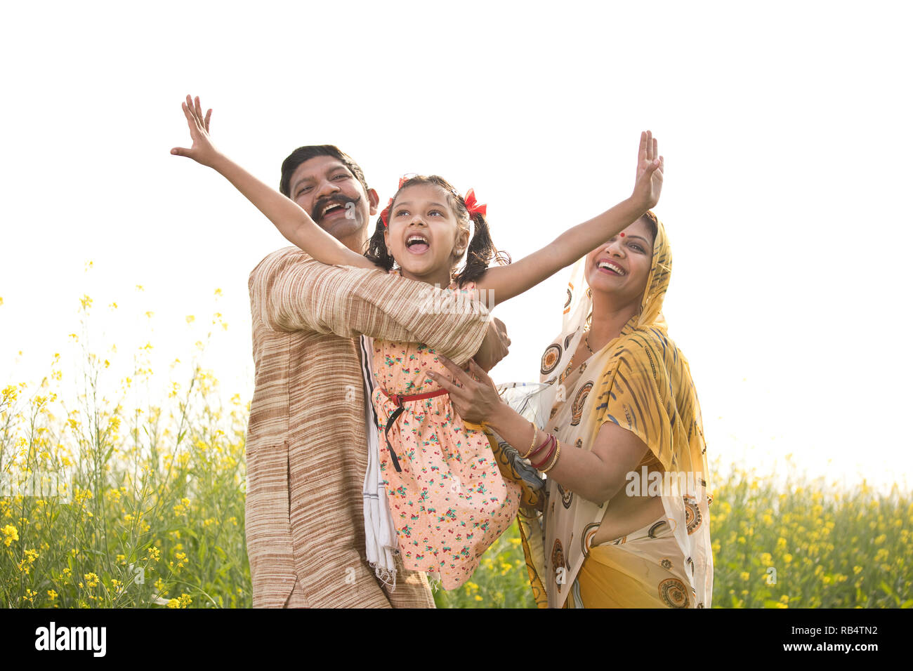 Les parents de l'Inde rurale avec sa fille s'amusant dans le colza champ agricole Banque D'Images