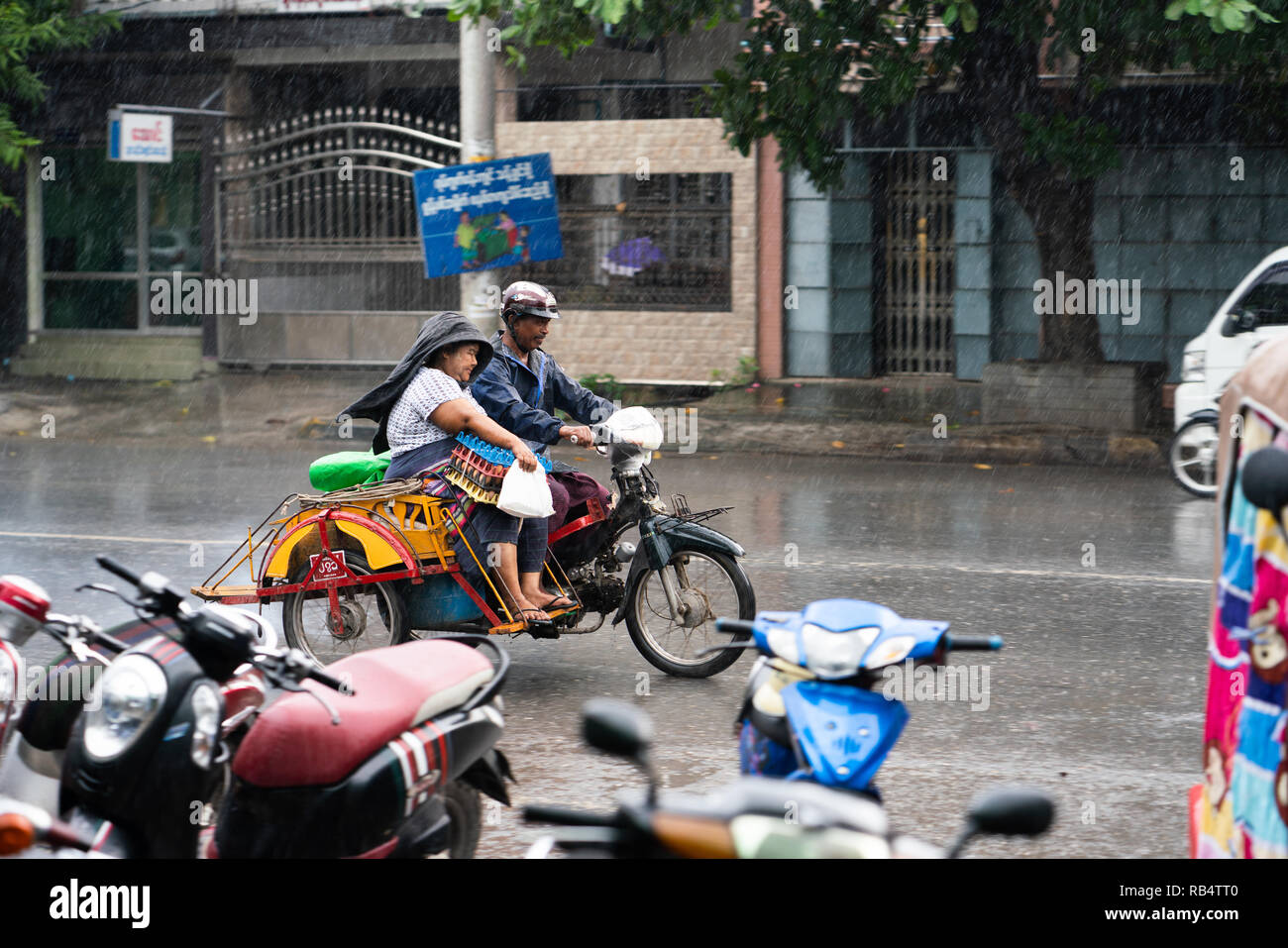 Couple en moto sous la pluie, Manadaly, Myanmar Banque D'Images