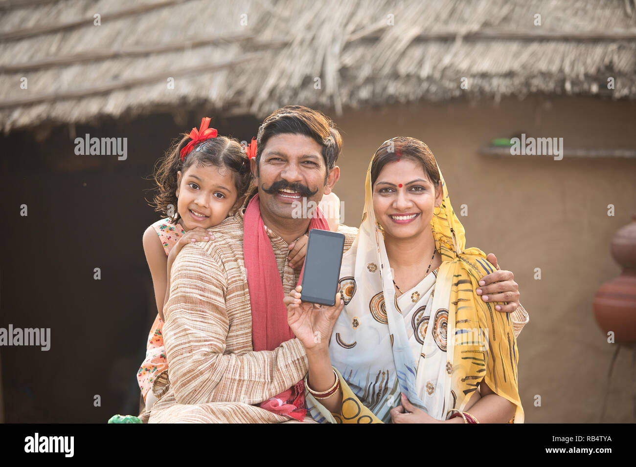 Portrait de famille rurales indiennes montrant nouveau téléphone mobile à village Banque D'Images