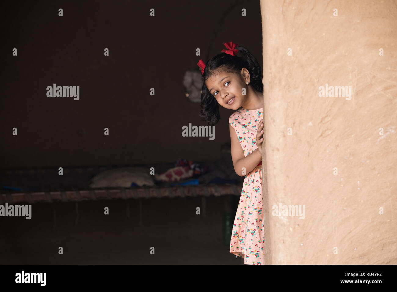 Little Indian girl peeking out de sa maison dans village Banque D'Images