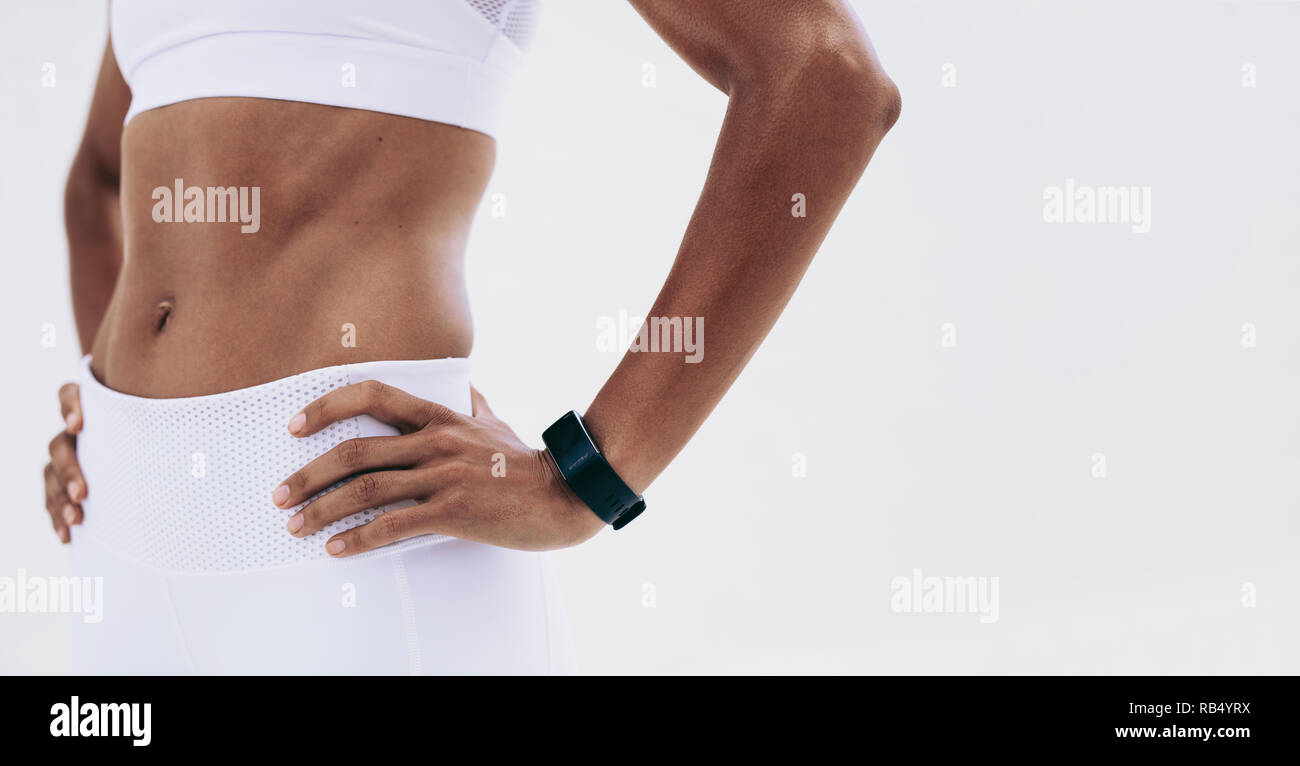 Close up de la partie médiane d'une athlète femme debout avec les mains sur la hanche. Le milieu de l'article d'une personne athlétique montrant un abdomen plat. Banque D'Images