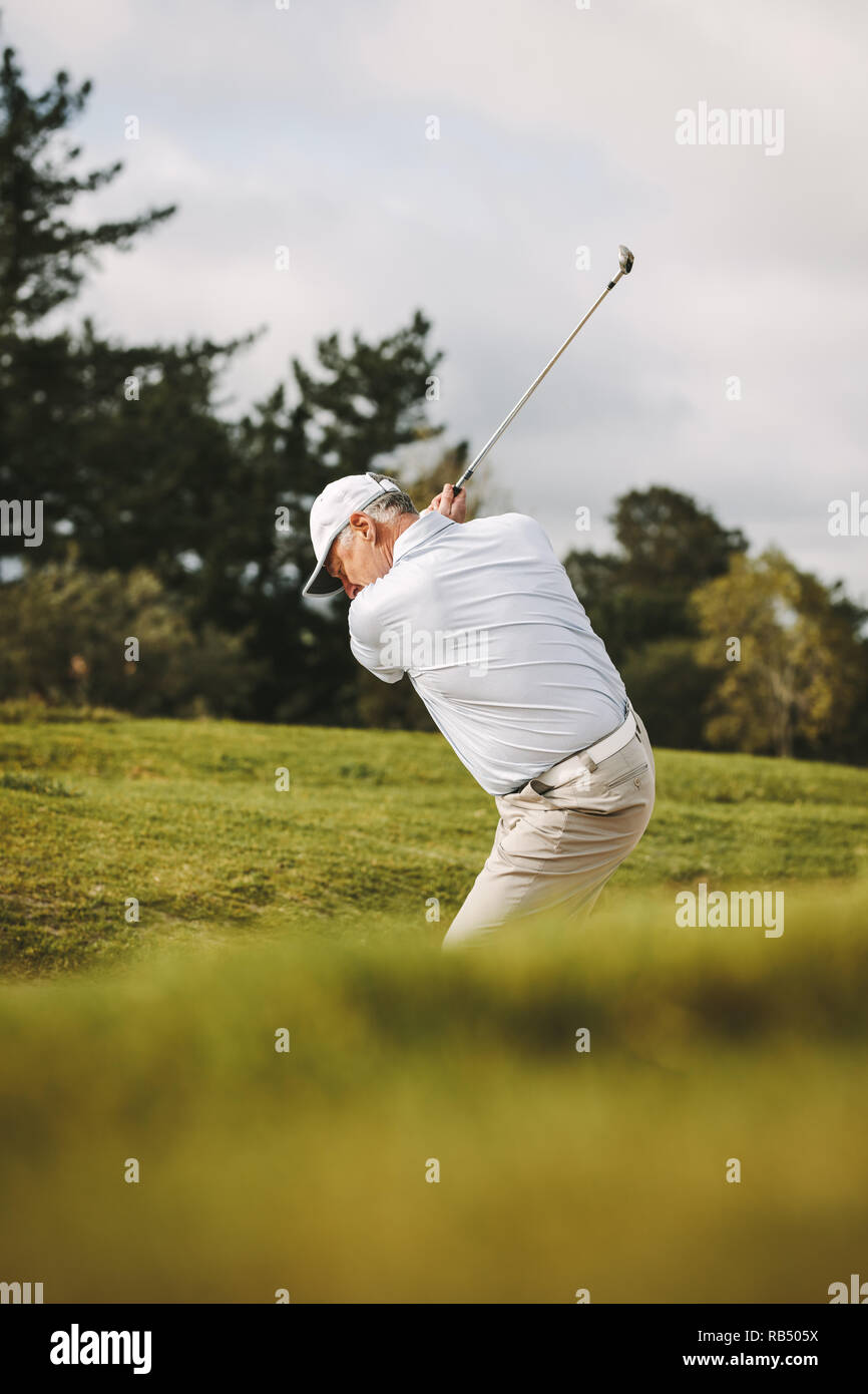 Golfeur aîné professionnel jouer au golf sur le parcours. L'homme de frapper la balle d'un bunker de sable. Banque D'Images