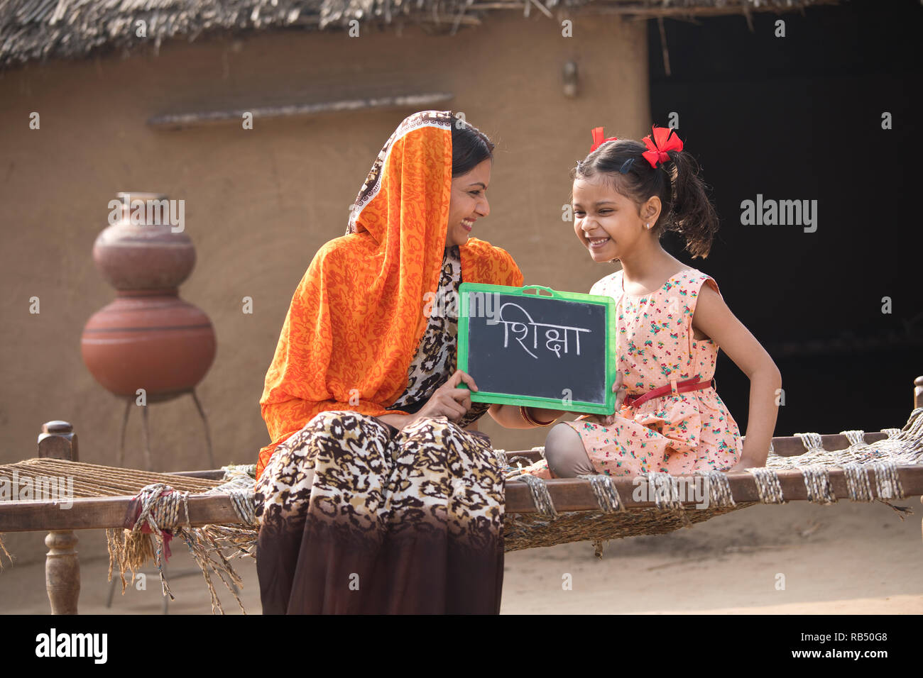 Heureuse mère indienne avec sa fille tenant assis sur ardoise lit traditionnel dans le village Banque D'Images