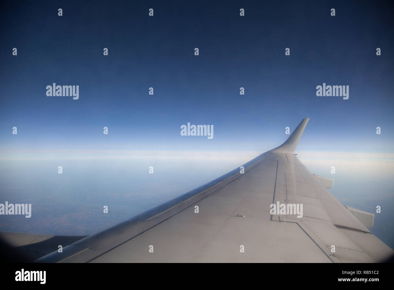 En regardant par la fenêtre sur l'aile d'un avion, en voyant les nuages ci-dessous Banque D'Images