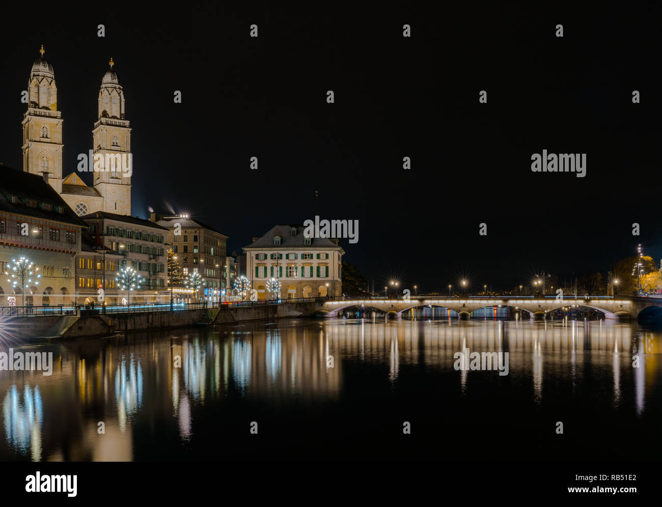 La ville de Zurich dans la nuit avec la rivière Limmat et la cathédrale Grossmünster et pont par des réflexions de lumières dans l'avant-plan Banque D'Images