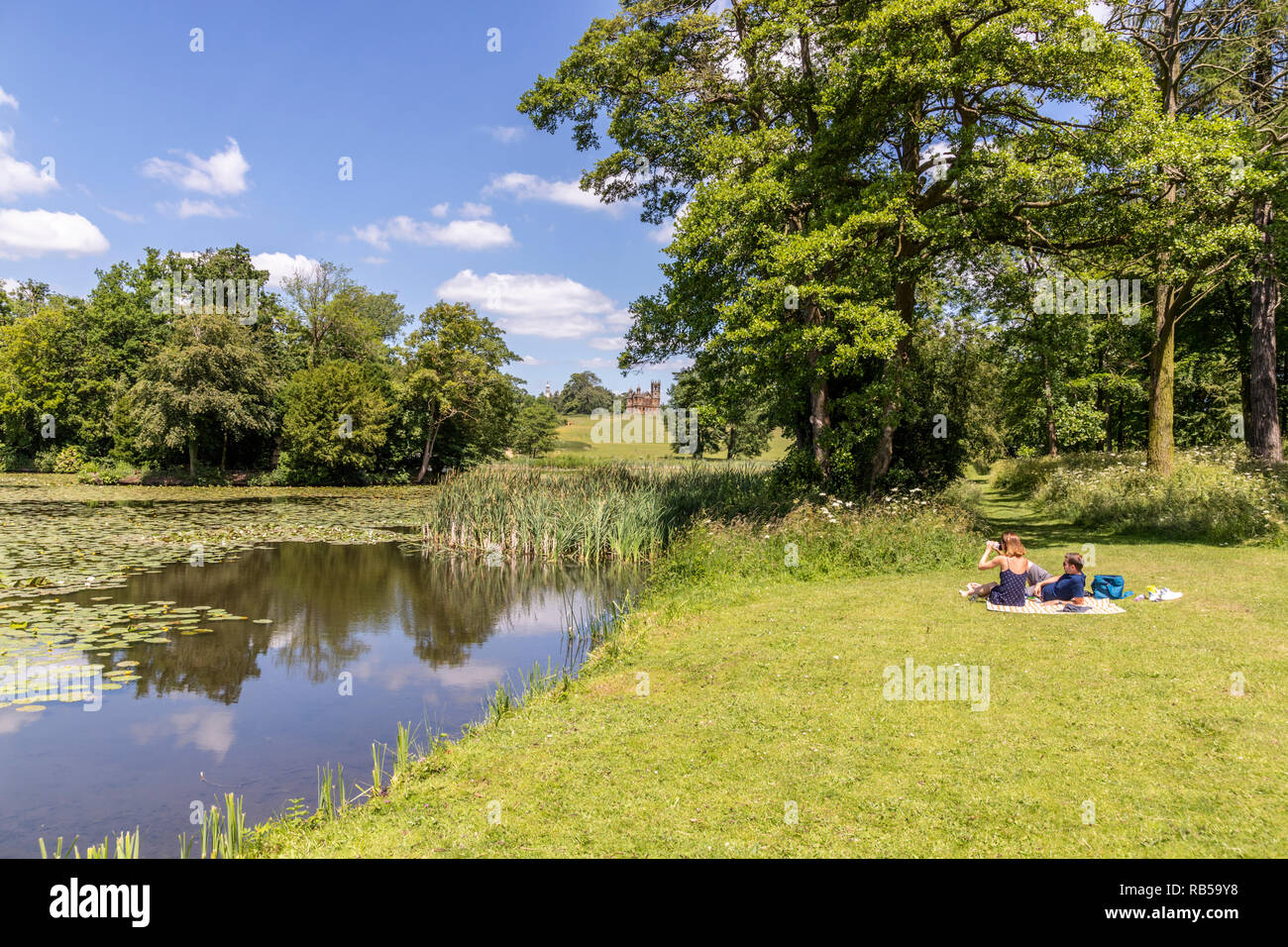 Un jeune couple appréciant un pique-nique au bord du lac à Stowe House Gardens, Buckinghamshire UK Banque D'Images