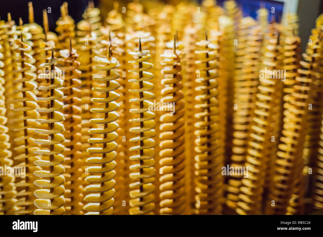 Pommes de terre frites, en spirale sur des bâtonnets de bois, en spirale. Vente de produits alimentaires sur le marché. Les aliments frits. L'alimentation de rue, une spirale sur un bâton de pommes de terre frites Banque D'Images