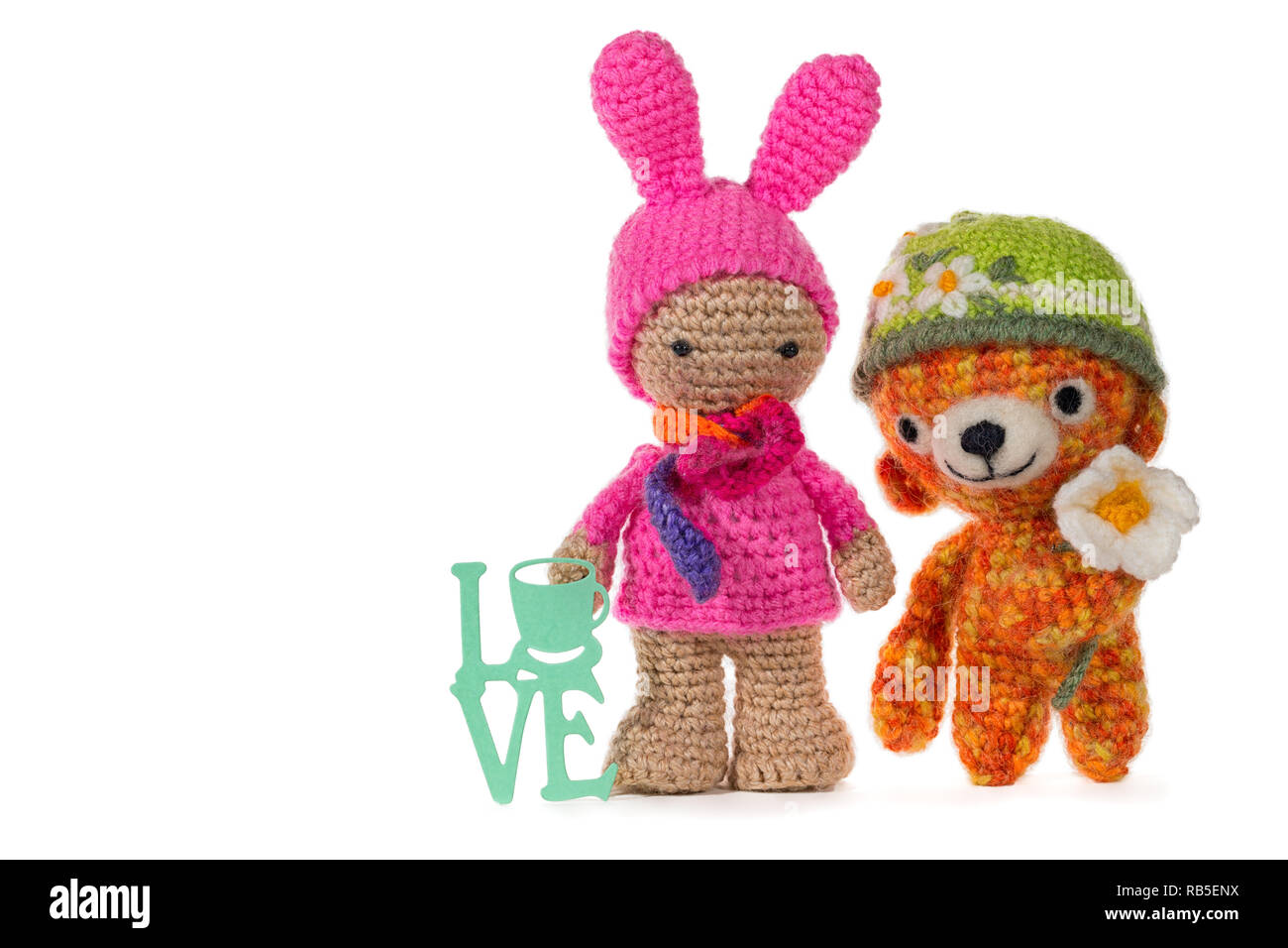 Habillé en bunny girl au crochet et crochet bear portant un chapeau avec une fleur avec signe de l'amour, sur fond blanc. Amigurumi. Handmade Banque D'Images