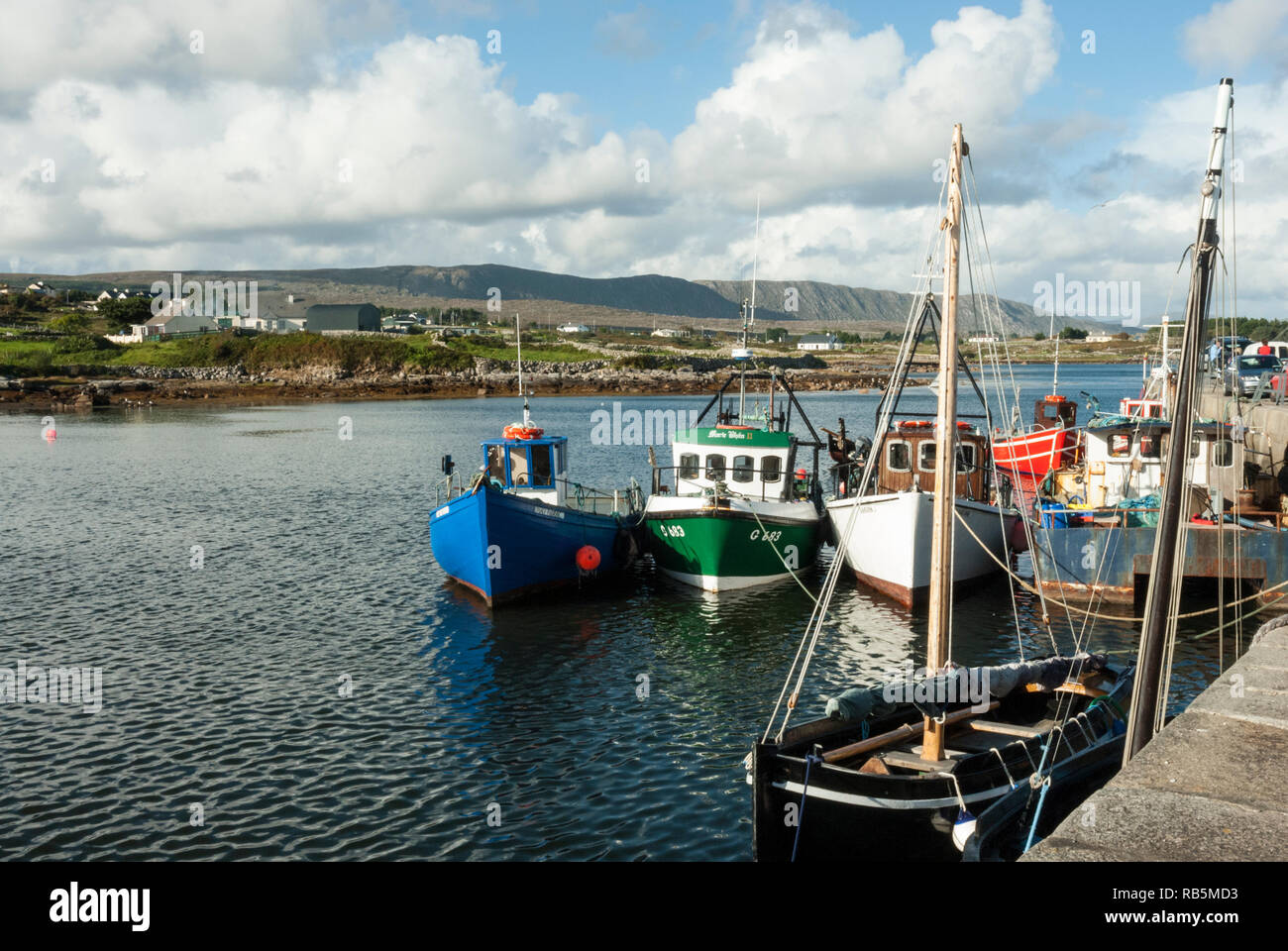 Les bateaux de pêche traditionnels colorés amarrés à un quai sur la côte ouest du comté de Galway, le Connemara, à la fin de l'été soleil. Banque D'Images