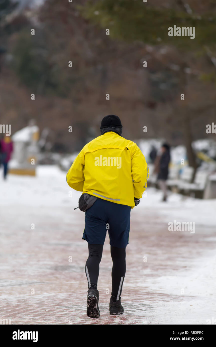 Glissière avec la veste sport jaune tournant dans winter park de derrière. Banque D'Images