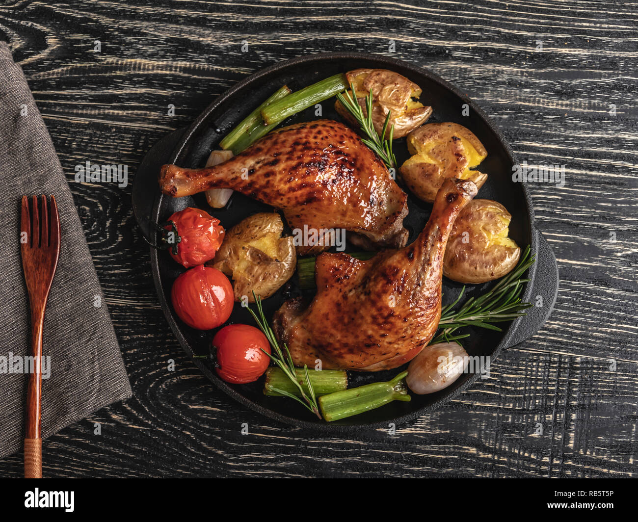 Cuisses de canard rôti avec pommes de terre, tomates dans une poêle , surface noire, Close up Banque D'Images