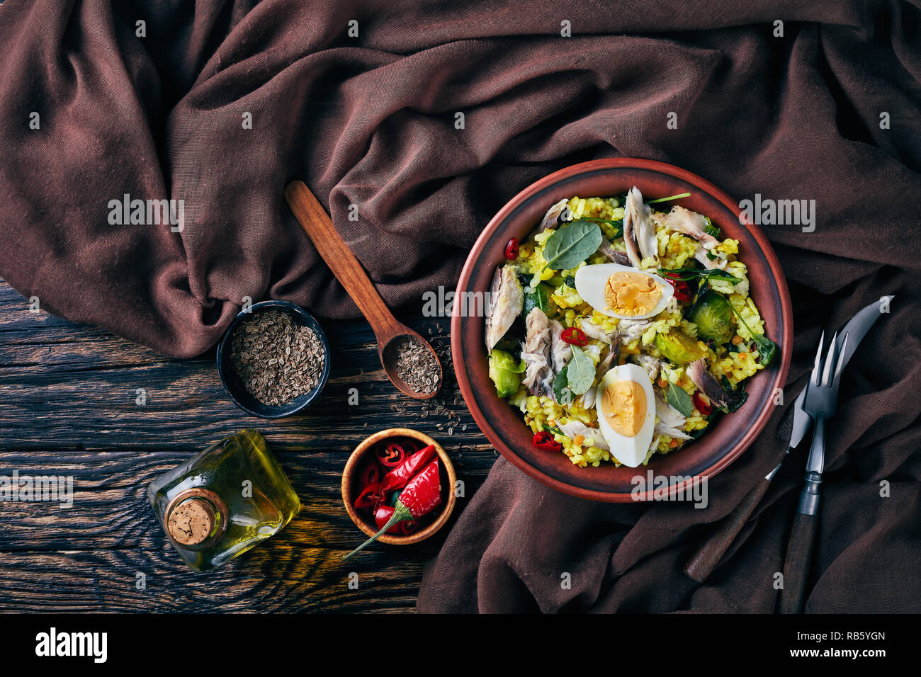 Kedgeree délicieux avec le poisson fumé émietté, œufs durs, du riz, chou frisé, chou de Bruxelles, les épices et les herbes dans un bol sur une vieille table en bois avec fenn Banque D'Images