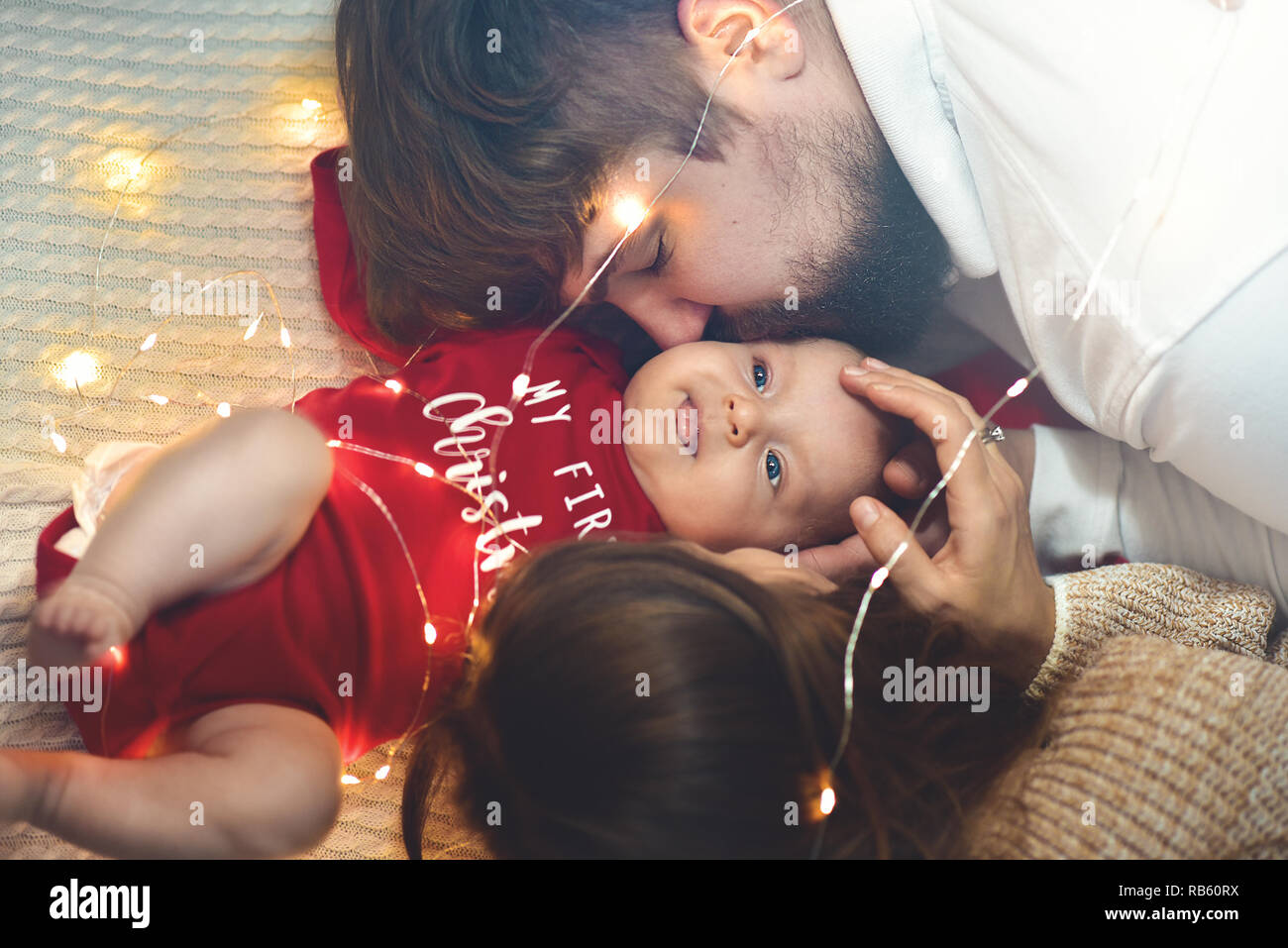 Vue d'en haut. Mère et père baisers bébé dans lit. Peu de nouveau-né dans un lit blanc. La parentalité Concepts. L'amour et bonheur. Prendre soin de la vie nouvelle. Banque D'Images