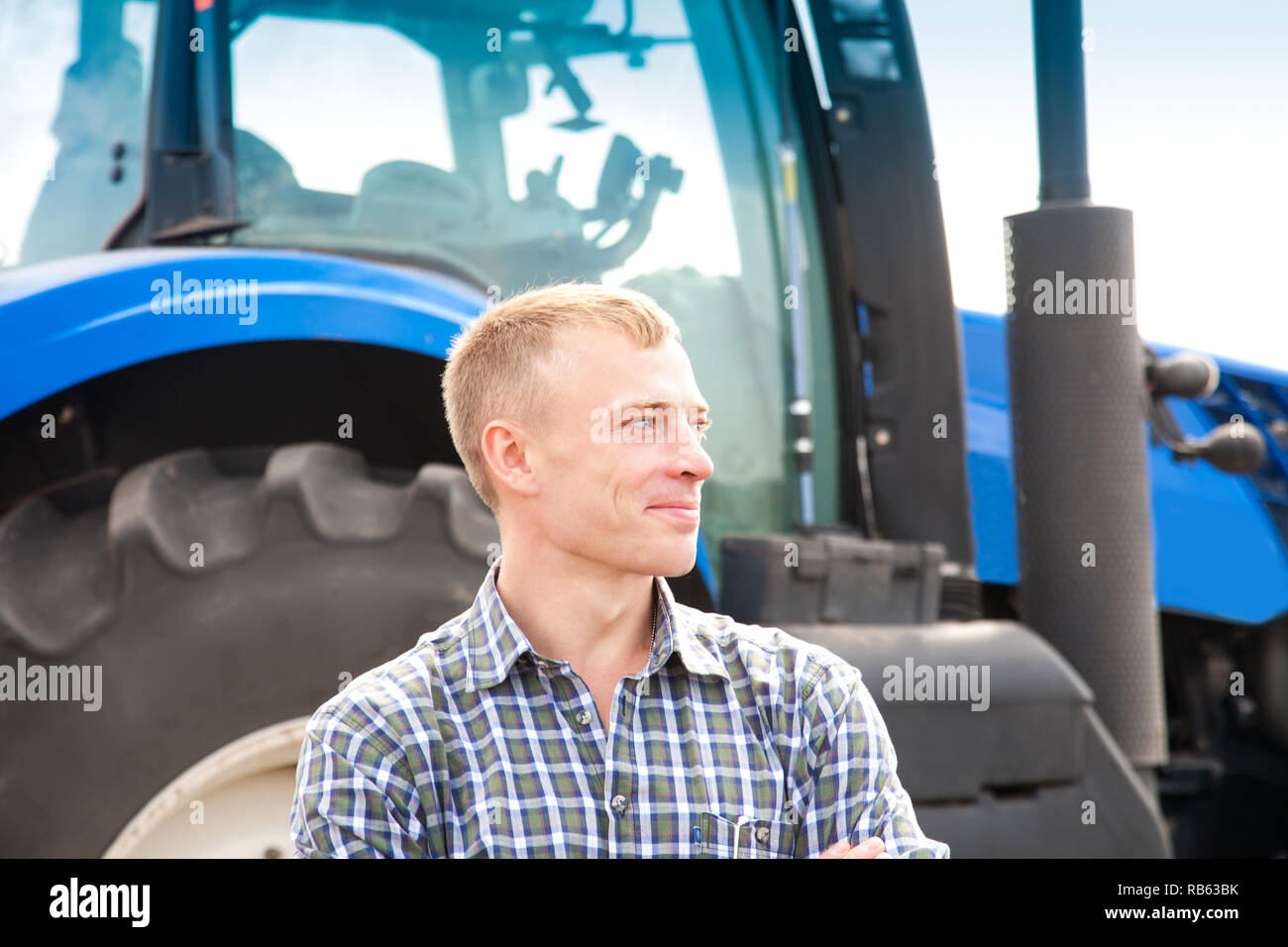 Jeune homme séduisant près d'un tracteur. Concept de l'agriculture et des travaux publics. Banque D'Images