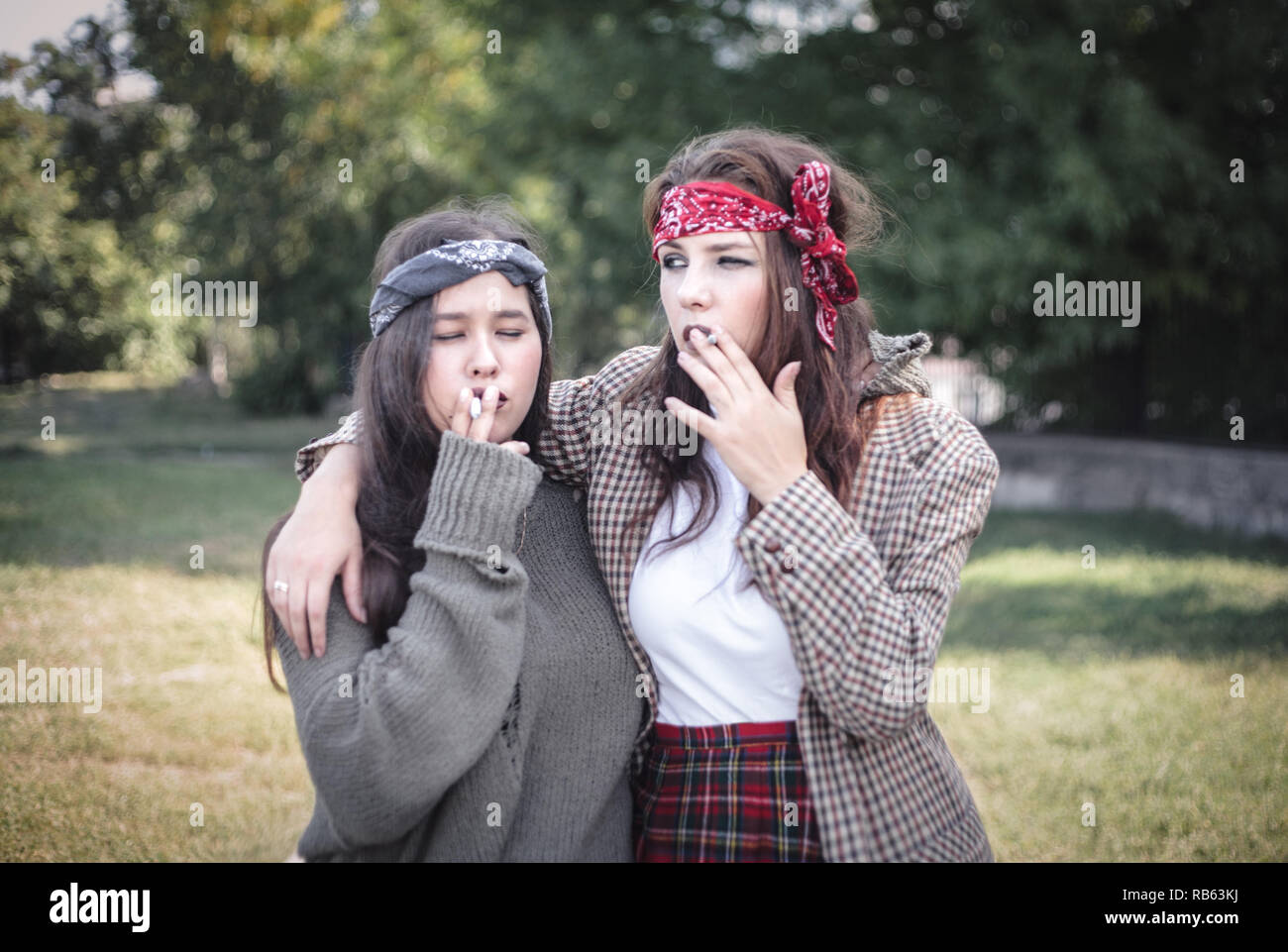 Deux filles habillées de façon informelle dans la rue avec des cigarettes. Problèmes d'adolescent. Banque D'Images