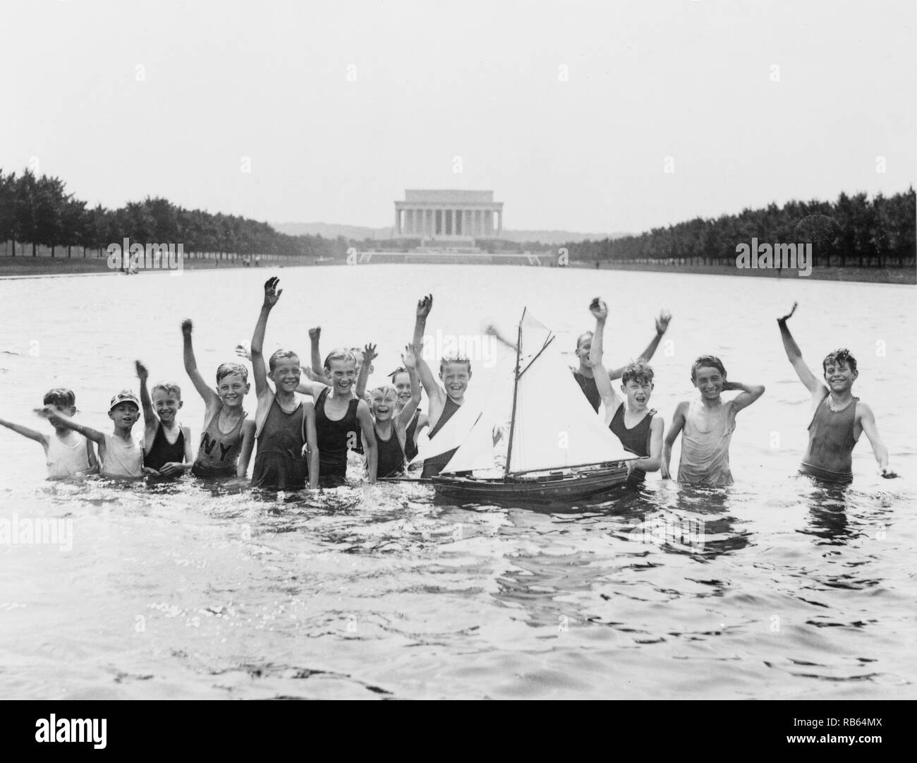 Photographie d'un groupe de jeunes garçons jouant dans le miroir d'eau, avec le Mémorial de Lincoln à l'arrière-plan. La photo montre le manque de financement approprié pour les piscines publiques à Washington. Datée 1926 Banque D'Images