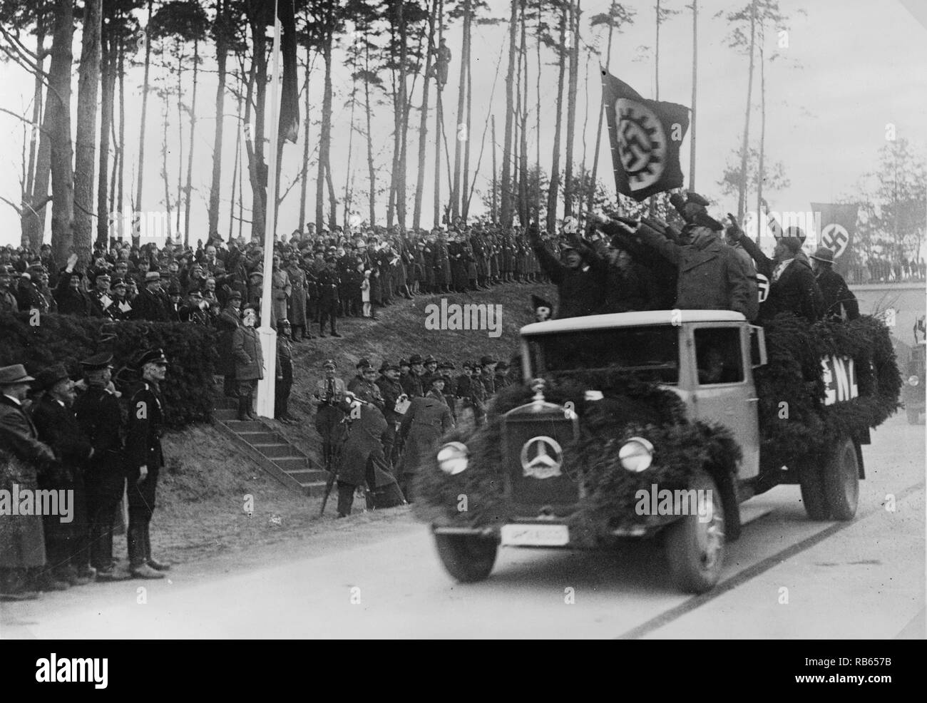 Hommes debout à l'arrière d'un camion Hermann Goering salut et d'autres fonctionnaires au cours de la cérémonie inaugurale de la nouvelle autoroute. Banque D'Images