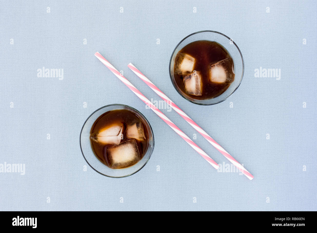 Deux pailles et deux verres remplis de glace café et des cubes de glace sur fond bleu avec beaucoup d'espace de copie. Vue d'en haut. Banque D'Images