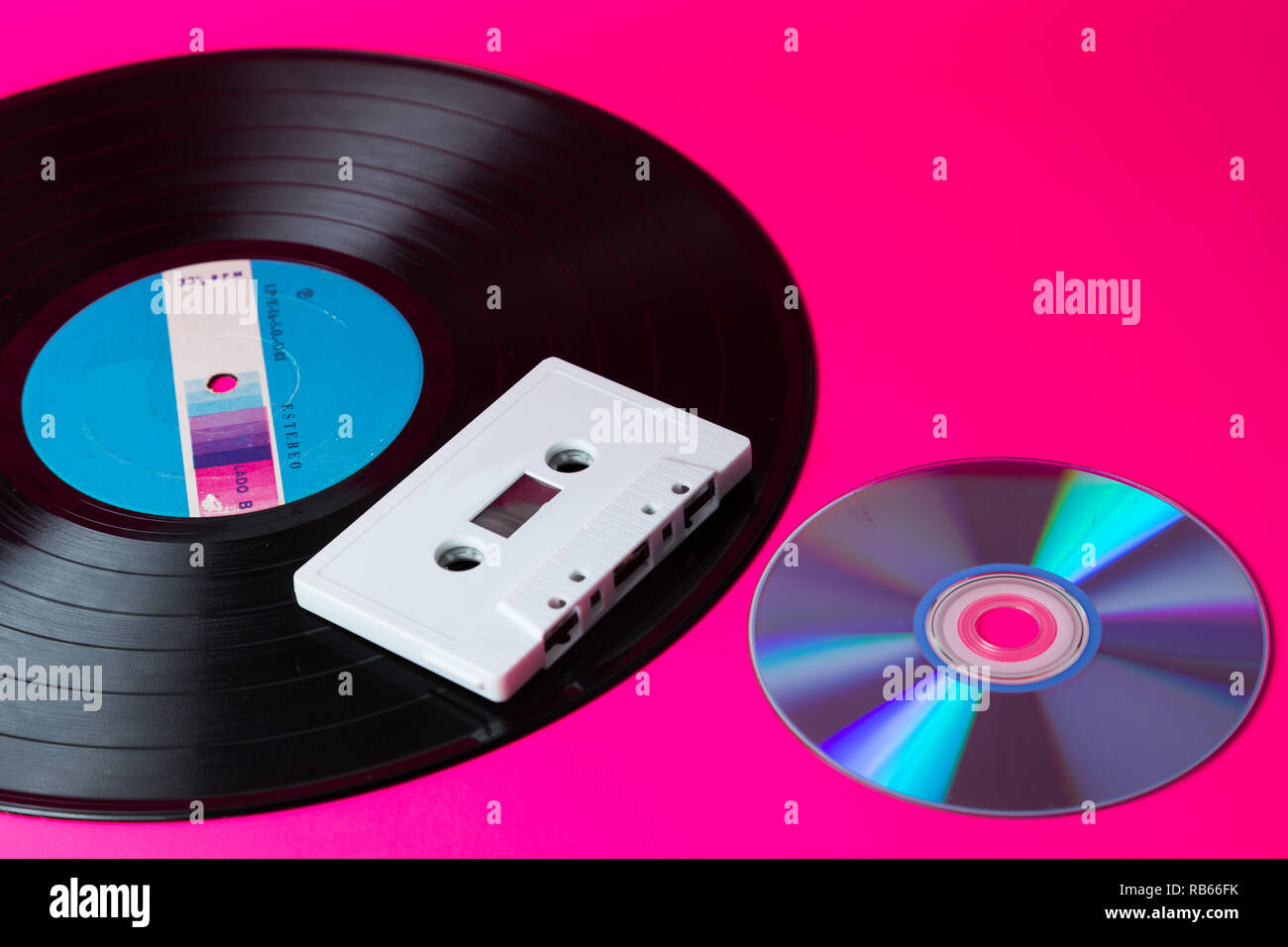 LP vinyl record une cassette audio et disque compact isolé en fond rose Banque D'Images