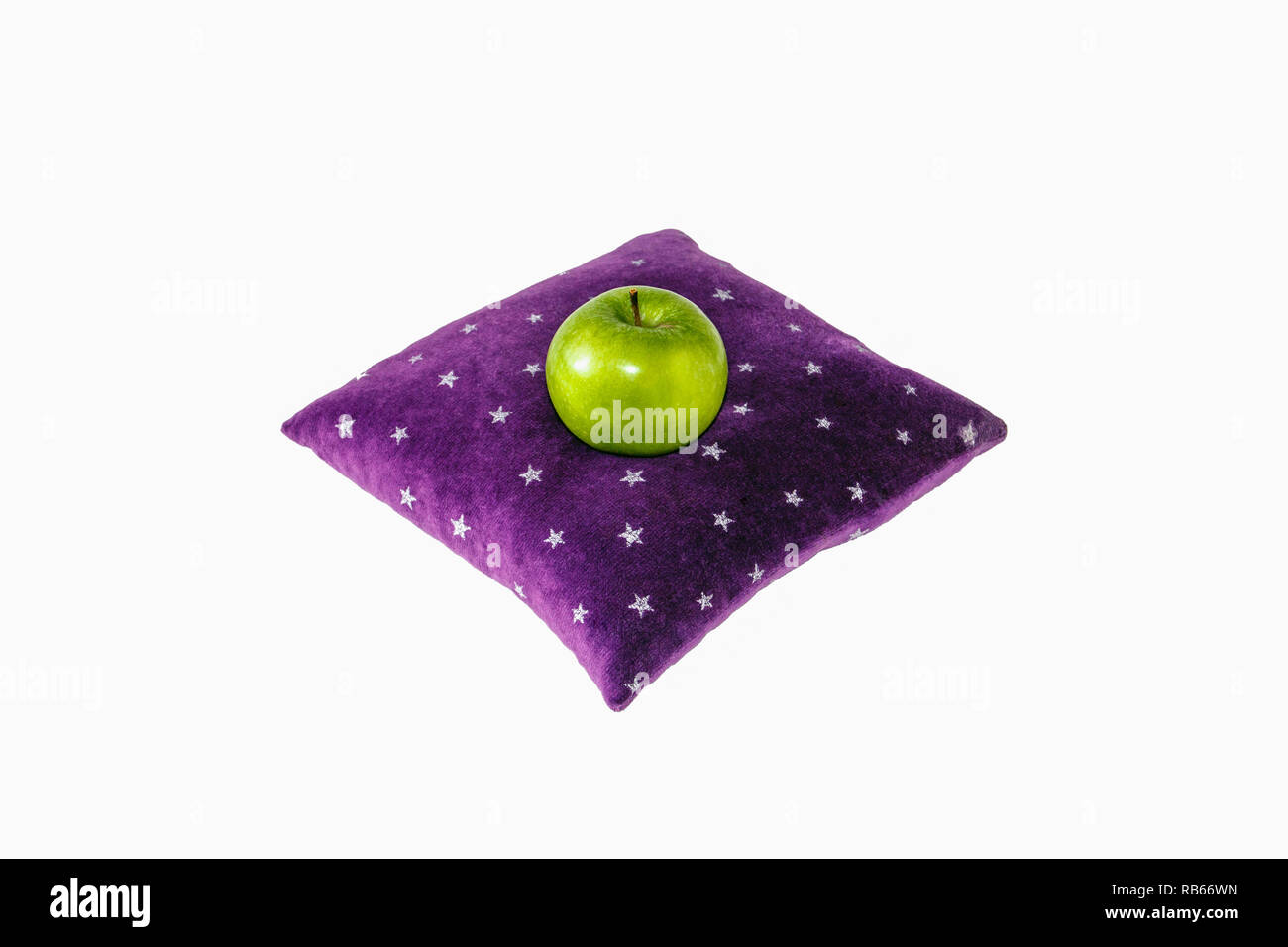 Un seul green Granny Smith apple assis sur un coussin de velours violet à motifs d'étoiles blanches, comme si floating Banque D'Images