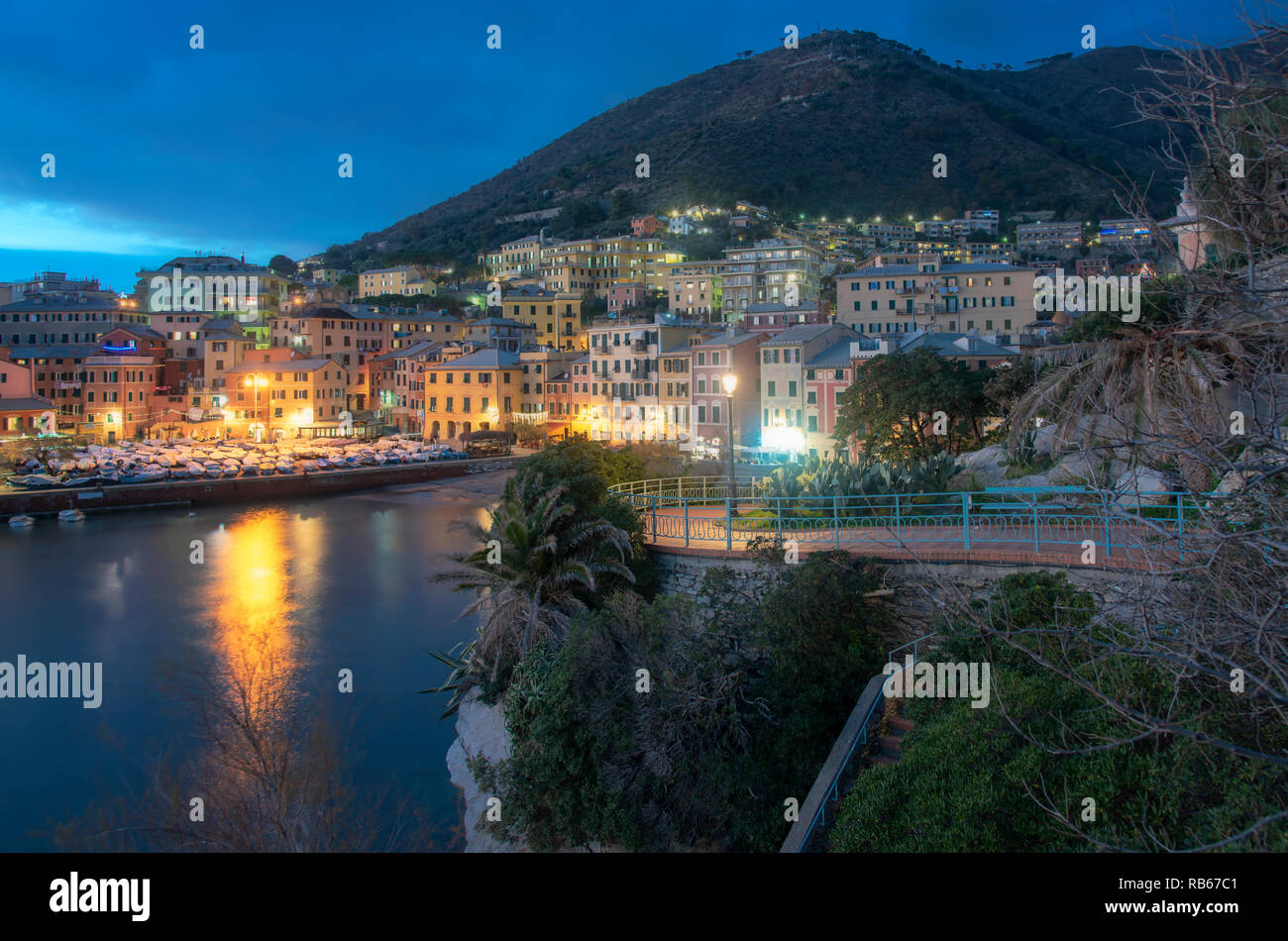 Scène de nuit à Nervi, Gênes, Italie, donnant sur le port avec ses bâtiments historiques sur la montagne et lumières réfléchissant sur l'eau calme dans la b Banque D'Images
