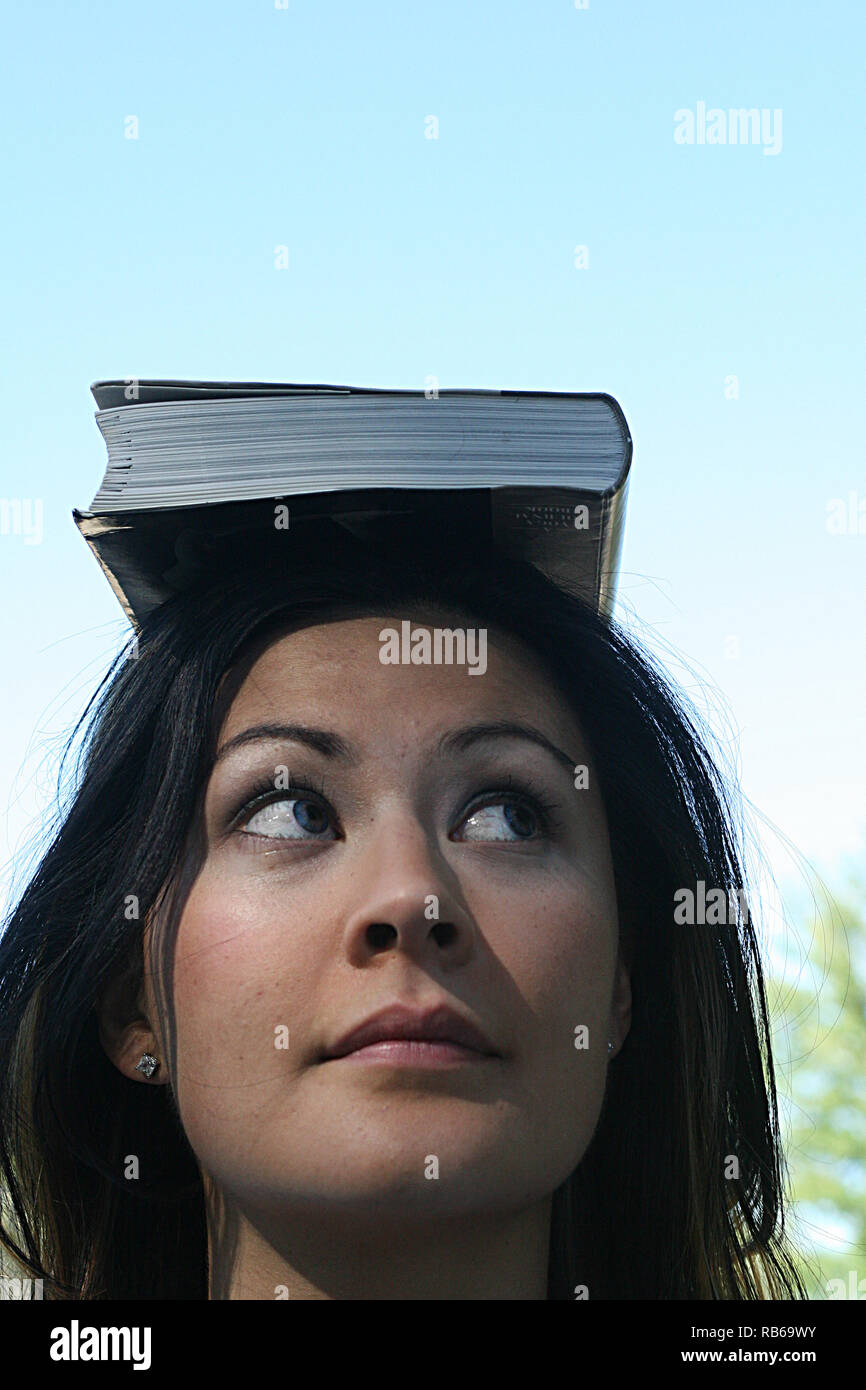 Brunette woman balancing un livre sur la tête. Banque D'Images