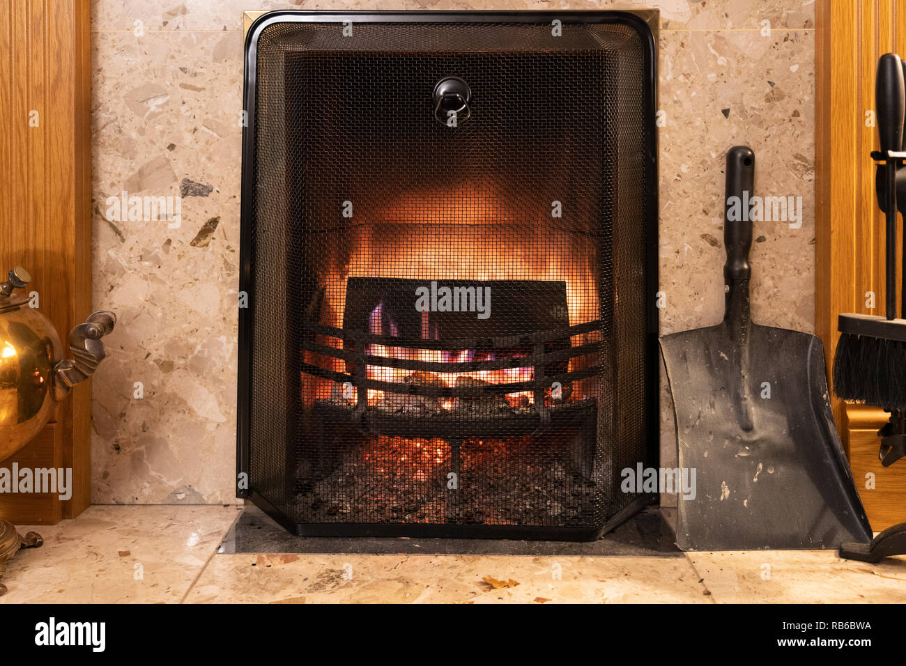 Une cheminée moderne avec la combustion du bois et d'un treillis de métal guard, UK Banque D'Images